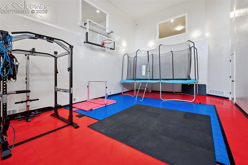 Image 44 of 50: Exercise room featuring a towering ceiling and visible vents