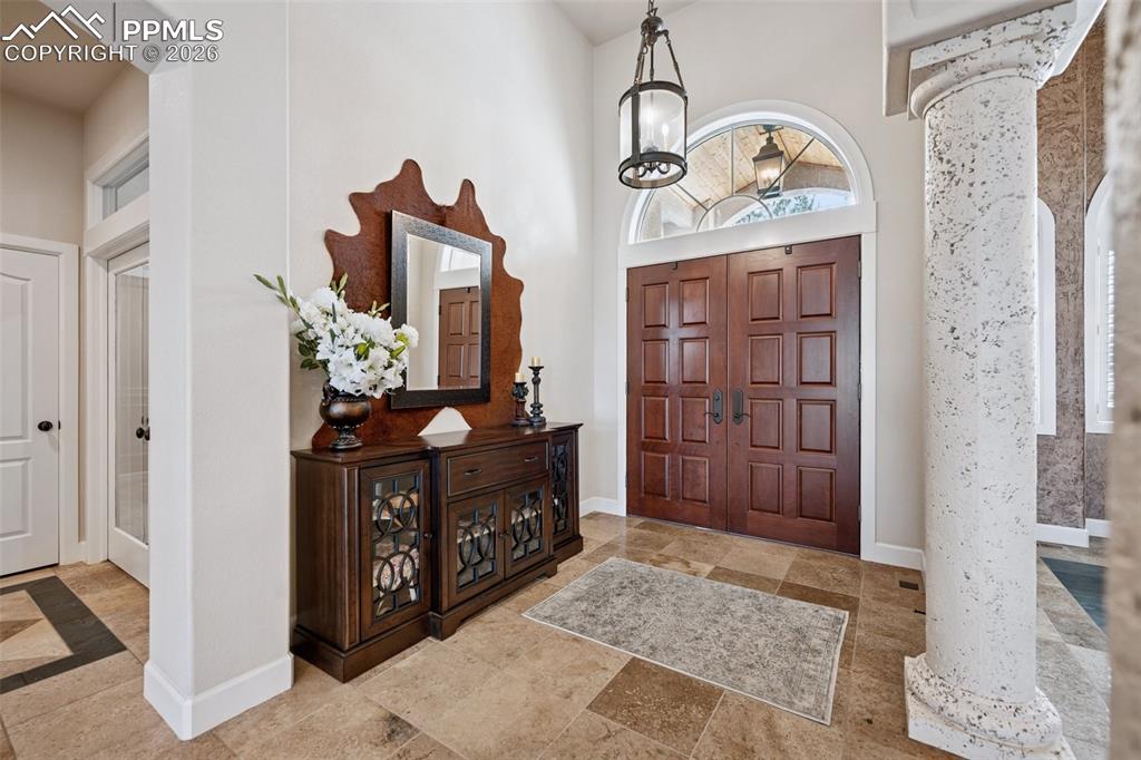 Image 6 of 50: Entrance foyer with arched walkways, baseboards, a high ceiling, and ornate