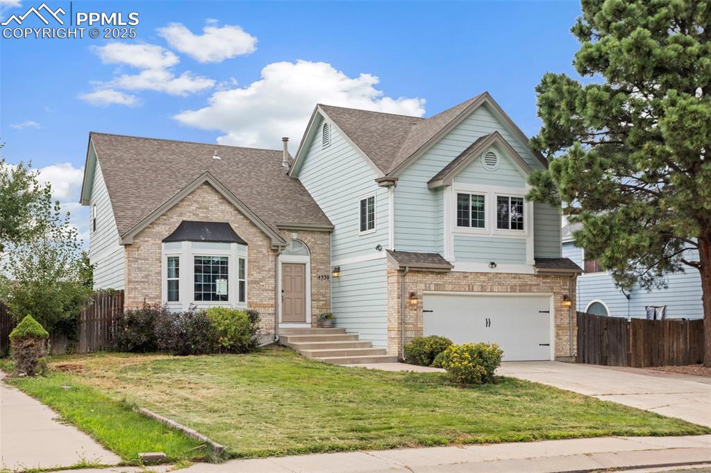 Caption: View of front of house featuring roof with shingles, an attached garage, brick siding, and concrete 