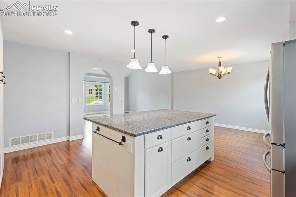 Image 10 of 37: Kitchen with freestanding refrigerator, dark stone countertops, decorative