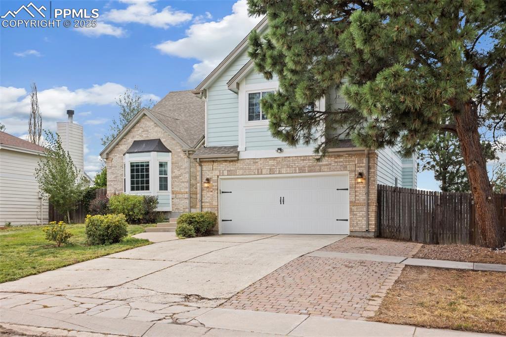 Image 2 of 37: Traditional home with brick siding, an attached garage, concrete driveway,