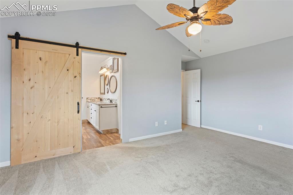 Image 25 of 37: Unfurnished bedroom featuring light carpet, high vaulted ceiling, ensuite b