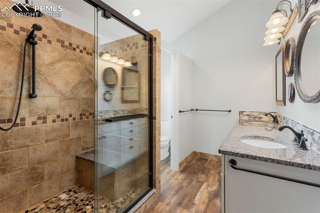 Image 26 of 37: Bathroom with dark wood-style flooring, a stall shower, and recessed lighti