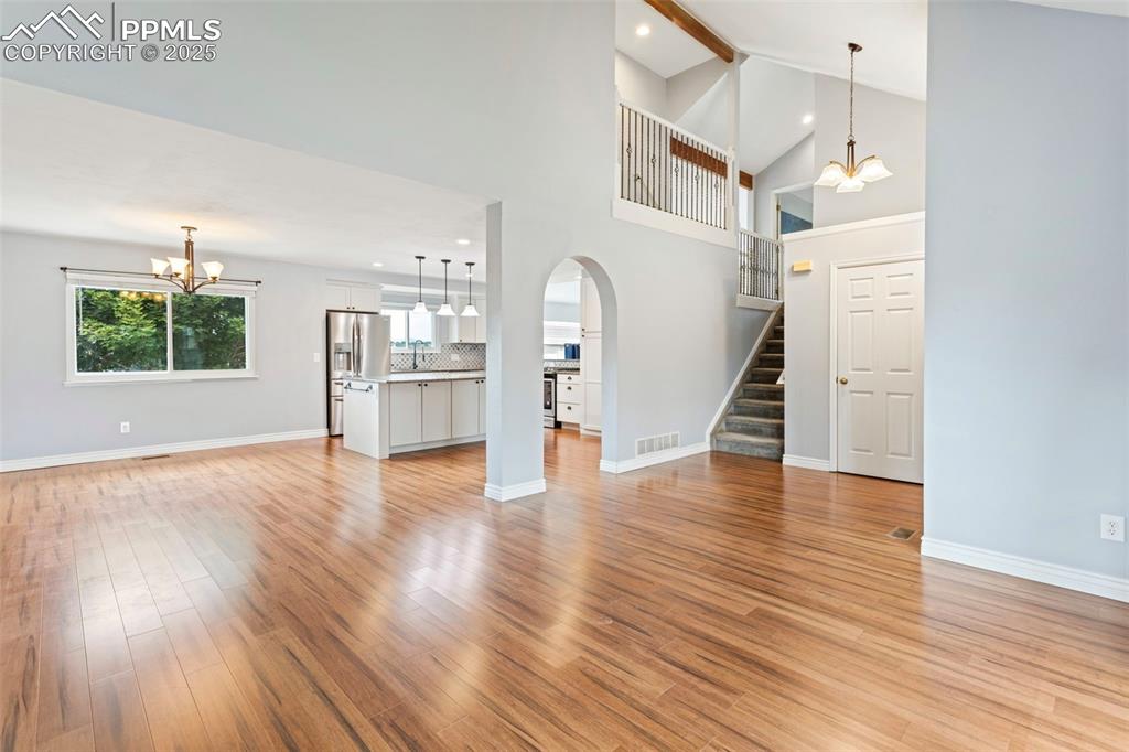 Image 6 of 37: Unfurnished living room featuring a chandelier, stairs, light wood-type flo