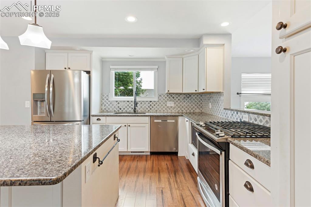 Image 9 of 37: Kitchen featuring dark stone countertops, appliances with stainless steel f