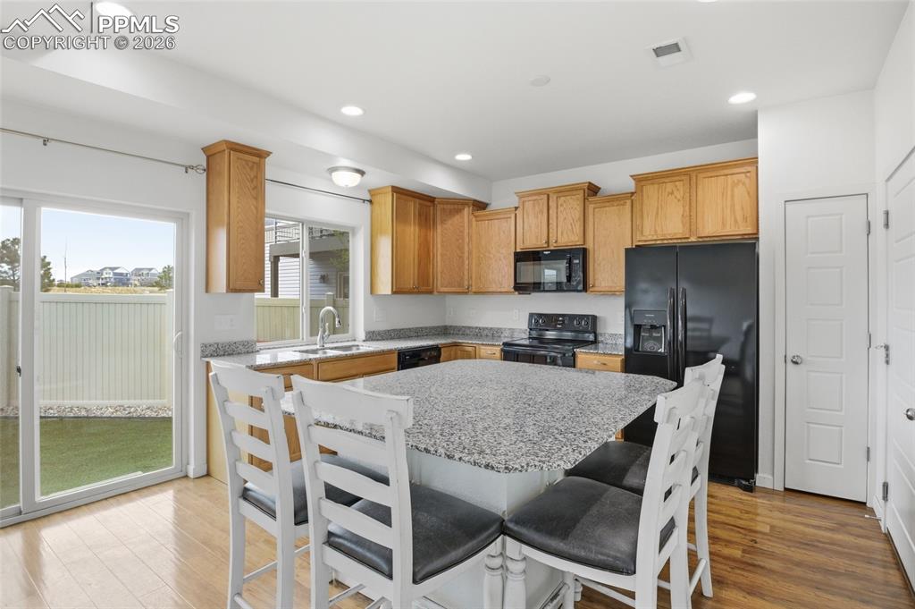 Image 10 of 29: Kitchen with black appliances, a center island, light stone counters, a kit