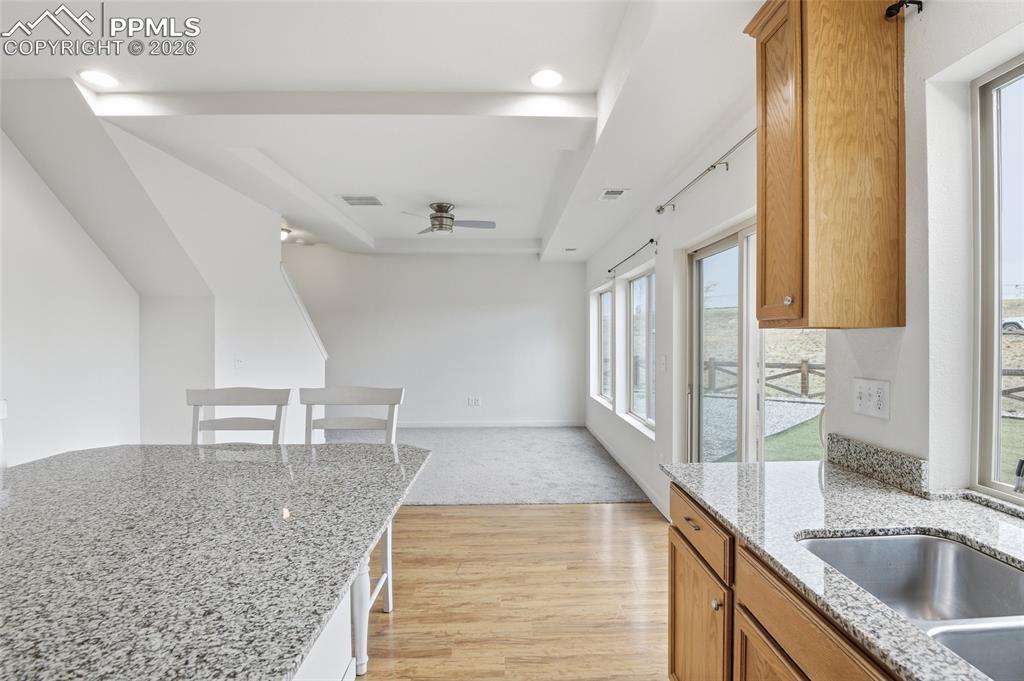 Image 11 of 29: Kitchen with wood finish cabinetry, light stone countertops, light wood-sty
