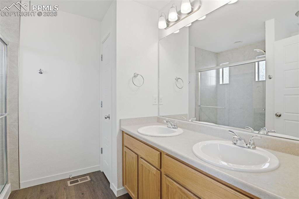 Image 15 of 29: Full bathroom featuring double vanity, a stall shower, and dark wood finish