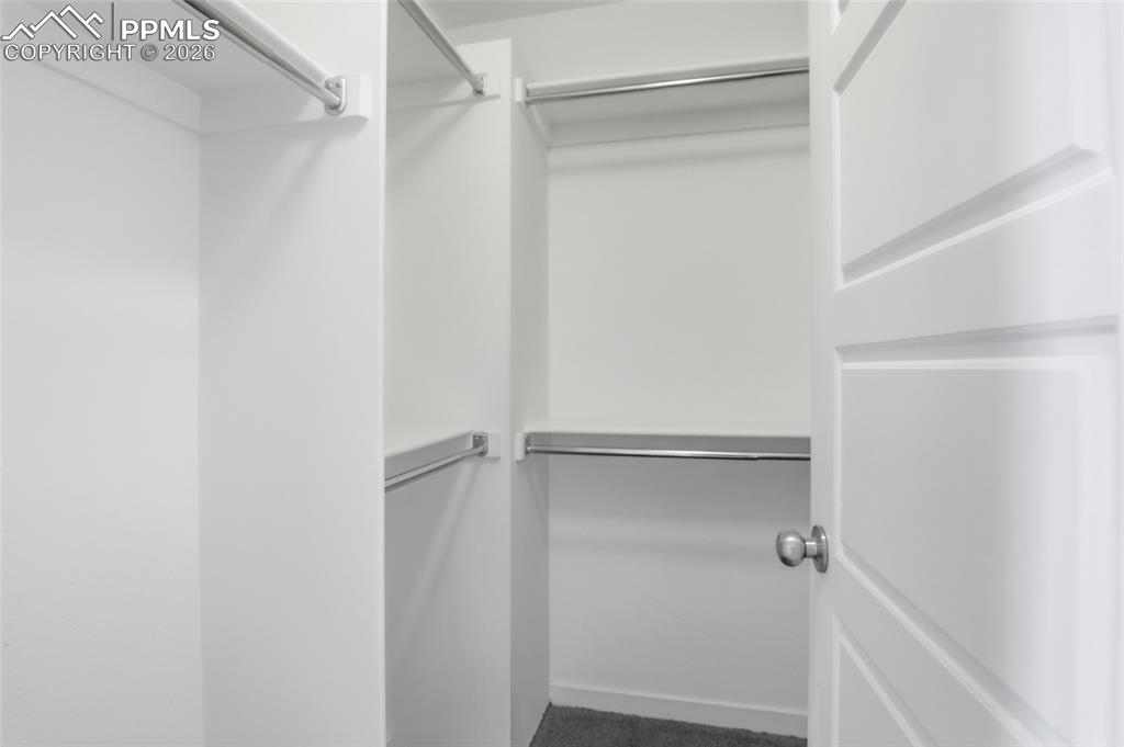 Image 17 of 29: Walk in closet with dark colored carpet