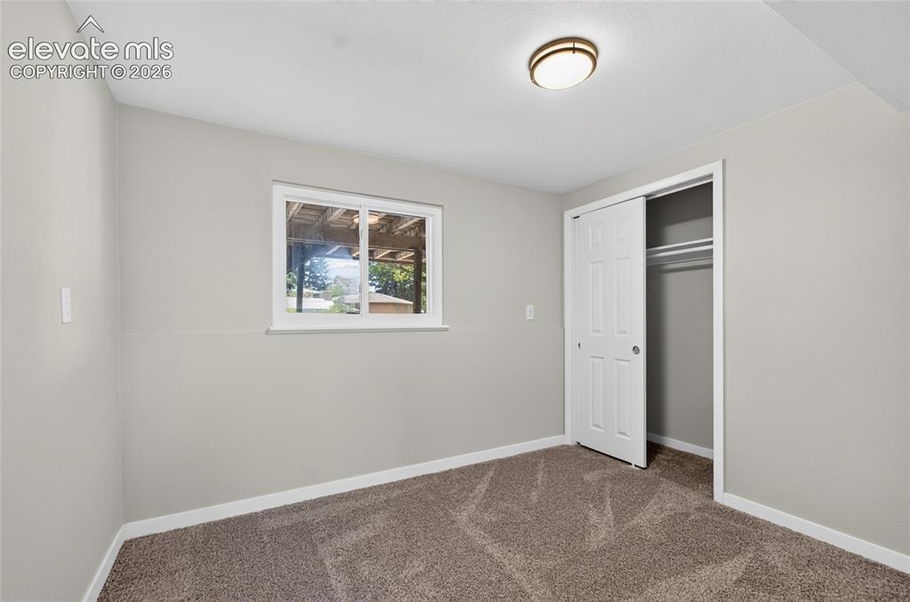Image 12 of 21: Carpeted room featuring a white-framed window, bi-fold closet doors, a ceil
