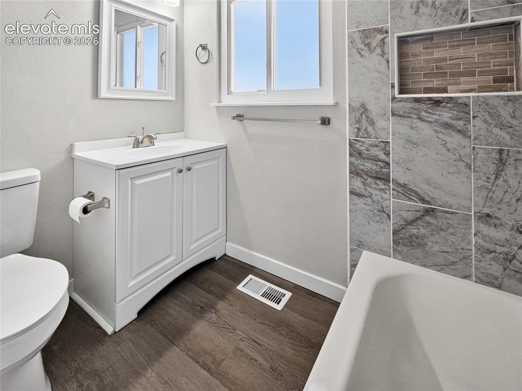 Image 13 of 21: Bathroom featuring a single-sink vanity with white cabinetry, a built-in ba