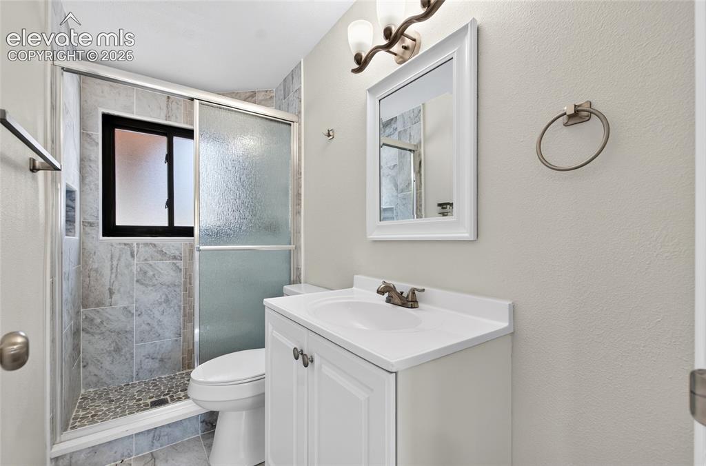 Image 14 of 21: Bathroom featuring a tiled shower with a sliding glass door, pebble floor,