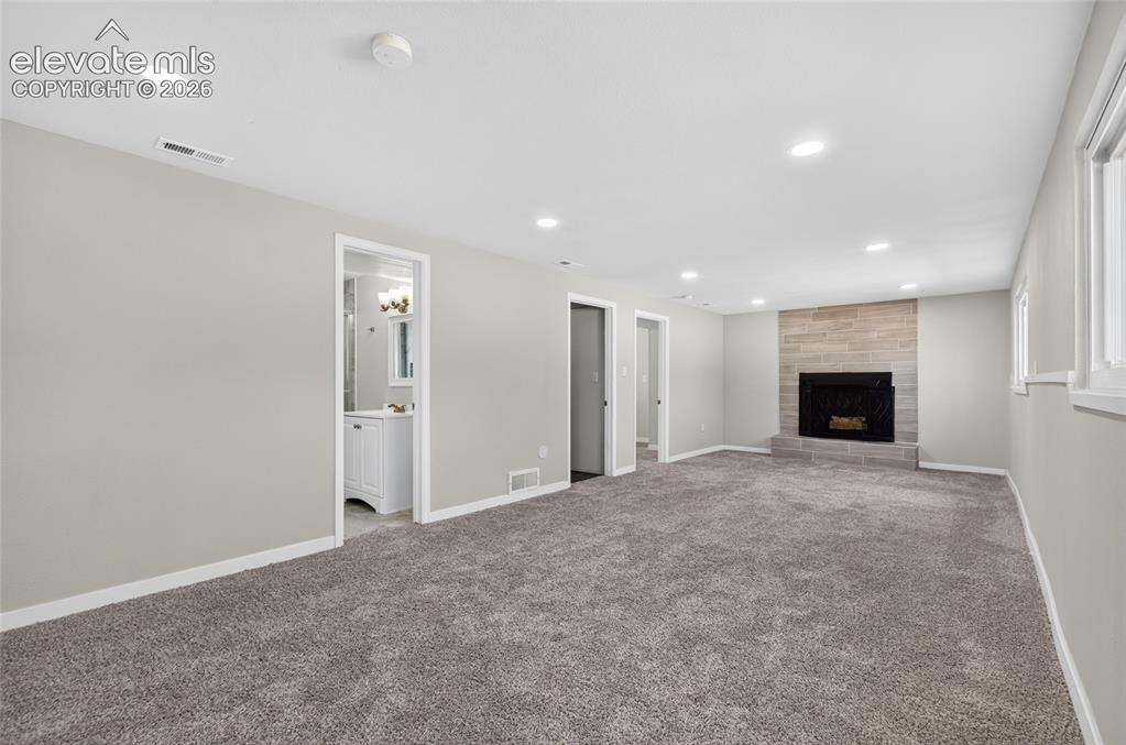 Image 15 of 21: Spacious room with plush gray carpeting, recessed ceiling lighting, a stone