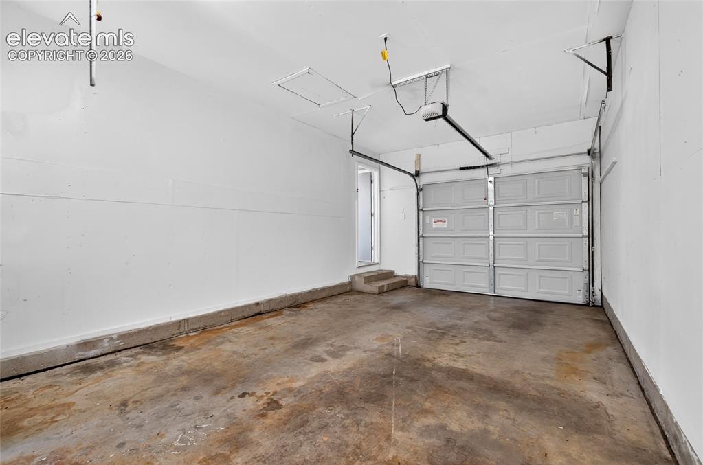 Image 18 of 21: Spacious garage featuring a concrete floor, white walls, and a paneled gara