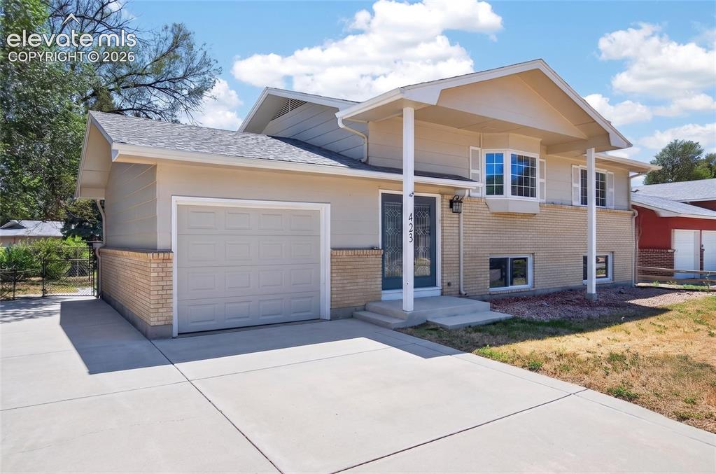 Image 2 of 21: Split-level residence featuring a light-colored stucco and brick exterior,