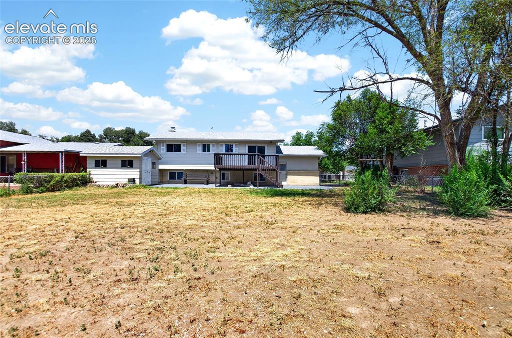 Image 20 of 21: Spacious backyard area featuring a multi-level residence with an upper-leve