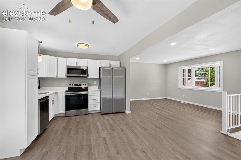 Image 5 of 21: Open-concept kitchen and living area featuring wood-finish flooring, white