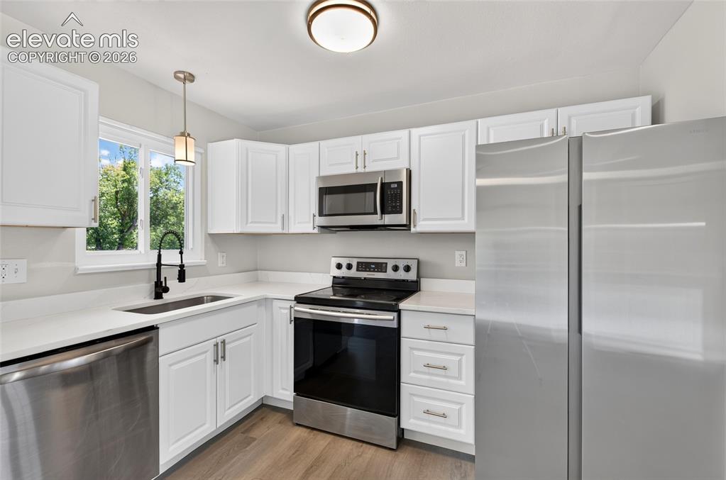 Image 7 of 21: Modern kitchen featuring white cabinetry, stainless steel appliances, light