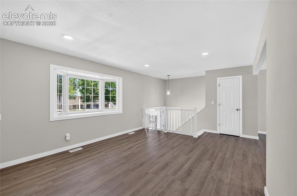 Image 8 of 21: Spacious room featuring wood-finish flooring, a large bay window, light gra