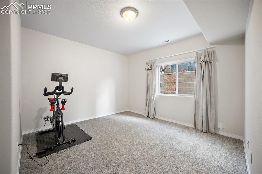 Image 38 of 50: Bedroom in the lower level being used as a workout room.