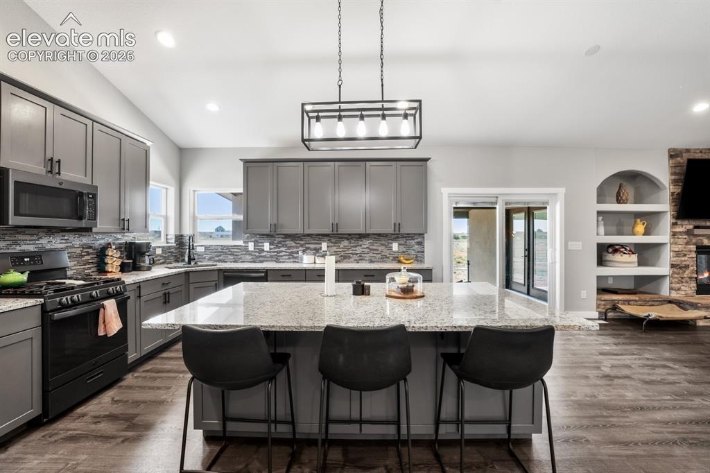 Image 10 of 50: Open-concept kitchen featuring an oversized island with seating, granite co