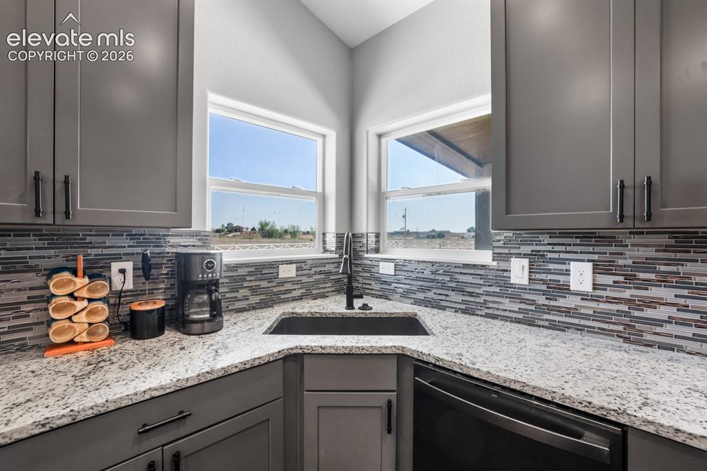 Image 11 of 50: Kitchen featuring gray cabinetry with black hardware, corner windows, a bla