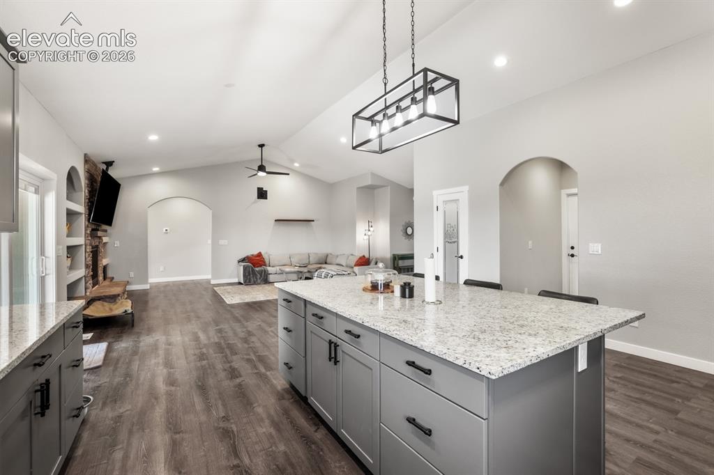 Image 12 of 50: Expansive kitchen island featuring a light-toned granite countertop and gra