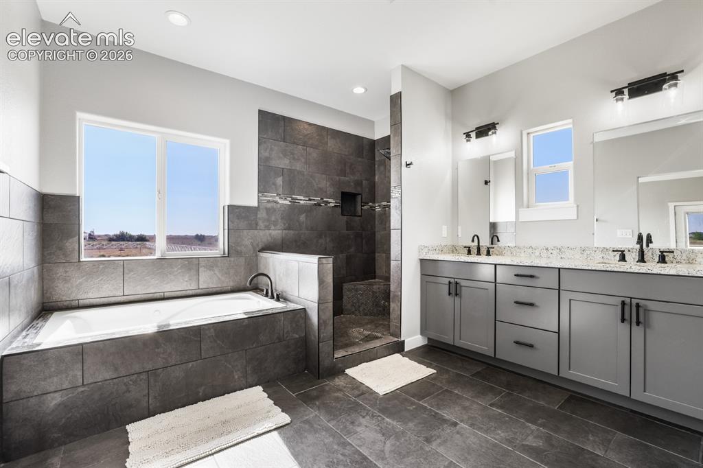 Image 15 of 50: Spacious bathroom featuring a built-in soaking tub, walk-in shower with til