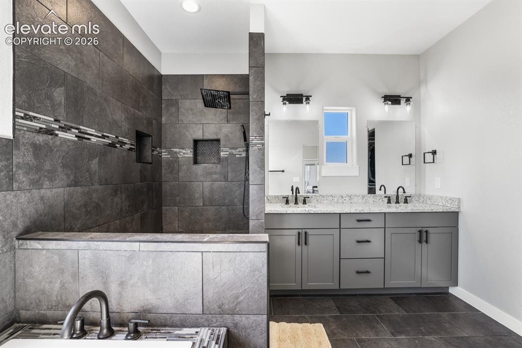 Image 16 of 50: Tiled walk-in shower with decorative tile accent band and integrated shelvi