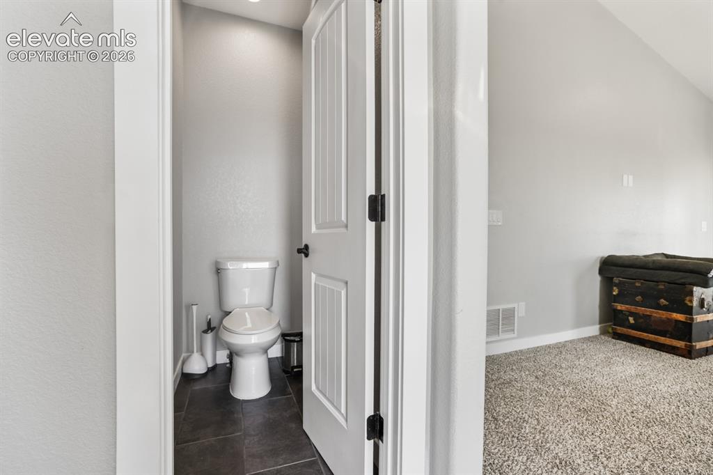 Image 17 of 50: Powder room with dark tile flooring, a white toilet, recessed lighting, and