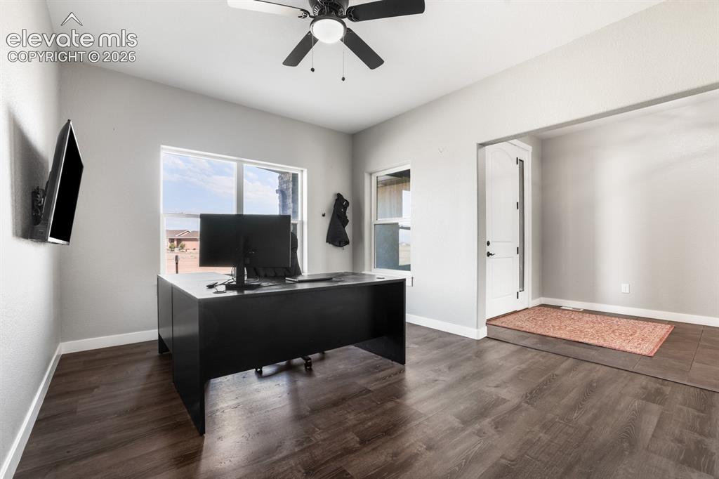 Image 20 of 50: Modern home office featuring a spacious layout with wood-finish flooring, a