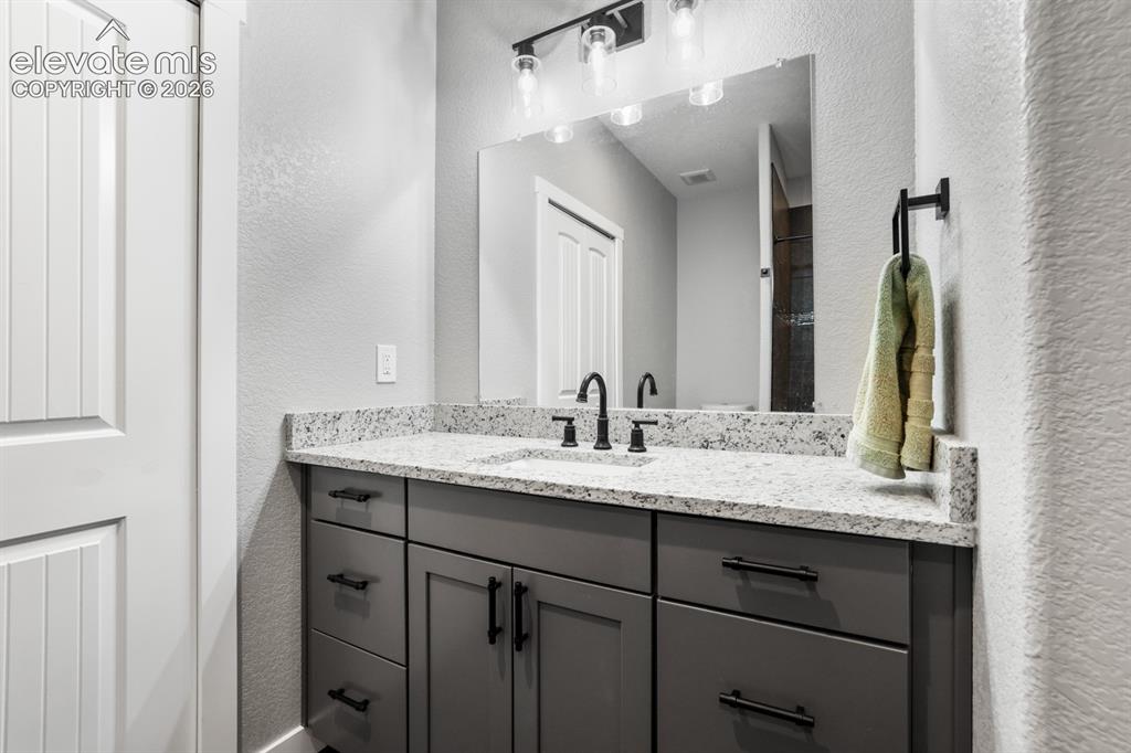 Image 28 of 50: Vanity with a speckled countertop, undermount sink, and matte black faucet