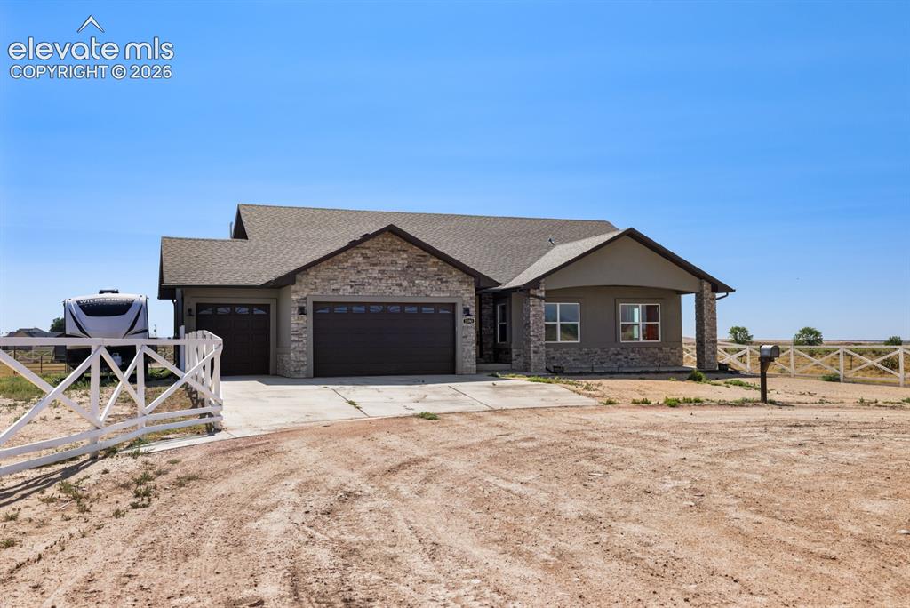Image 3 of 50: Ranch-style residence featuring a stone veneer and stucco exterior with a c