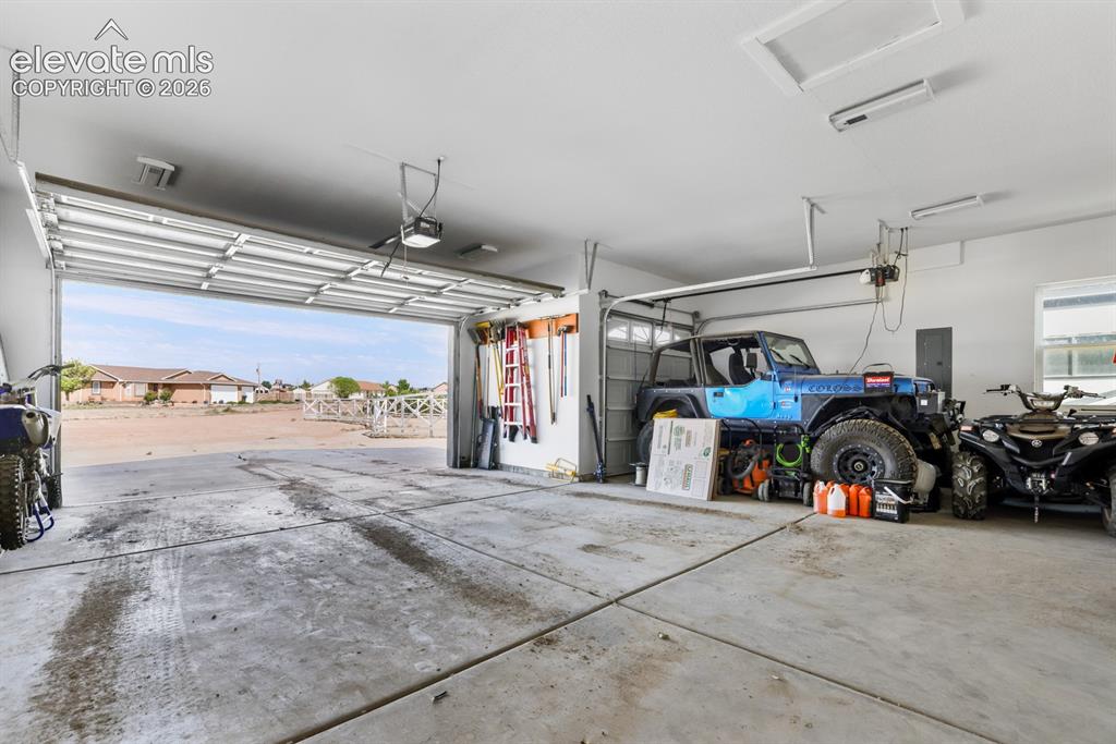 Image 33 of 50: Spacious garage with concrete flooring, automatic overhead door, and interi