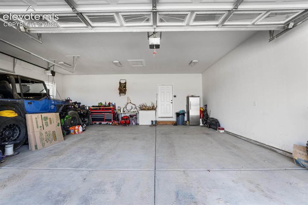 Image 34 of 50: Spacious two-car garage featuring a sectional overhead door, concrete floor
