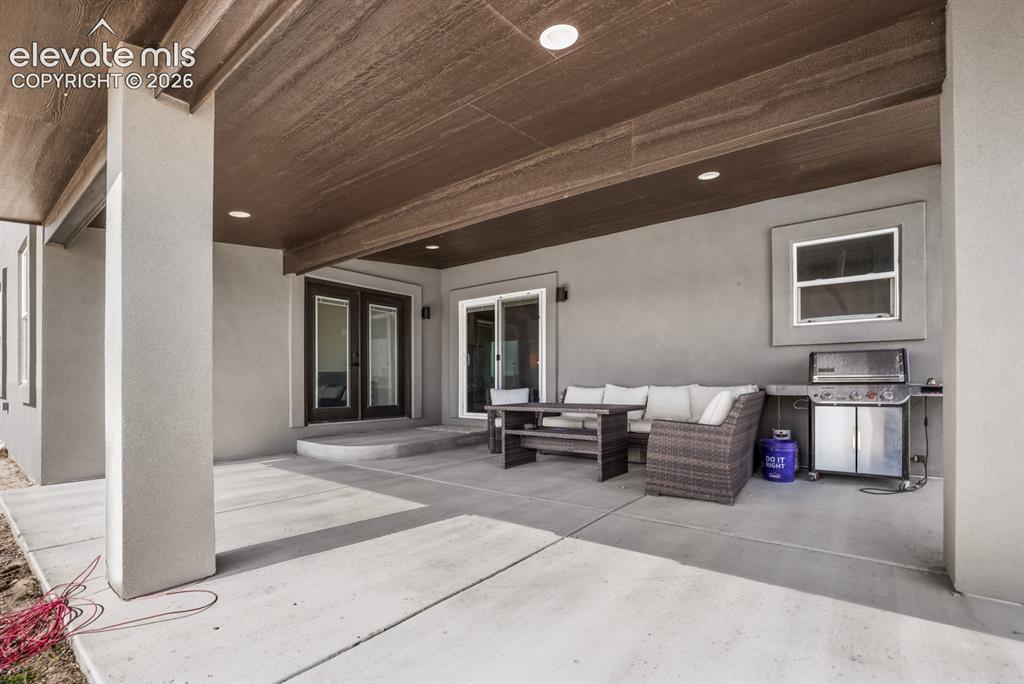 Image 36 of 50: Expansive covered patio featuring polished concrete flooring, wood-finish c