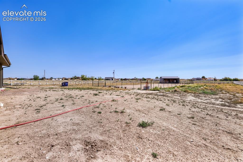Image 37 of 50: Expansive undeveloped lot with a partial perimeter fence and distant outbui