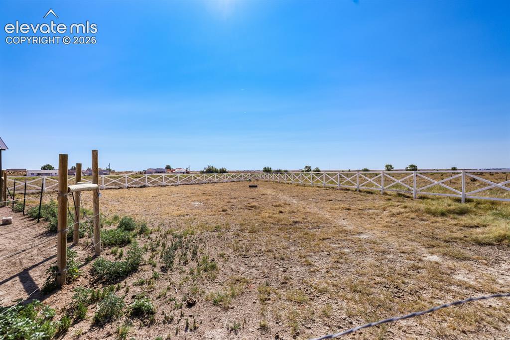 Image 42 of 50: Expansive open land area featuring a white cross-buck fence and a clear blu