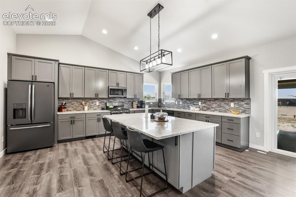 Image 7 of 50: Contemporary kitchen featuring a spacious center island with seating, a vau