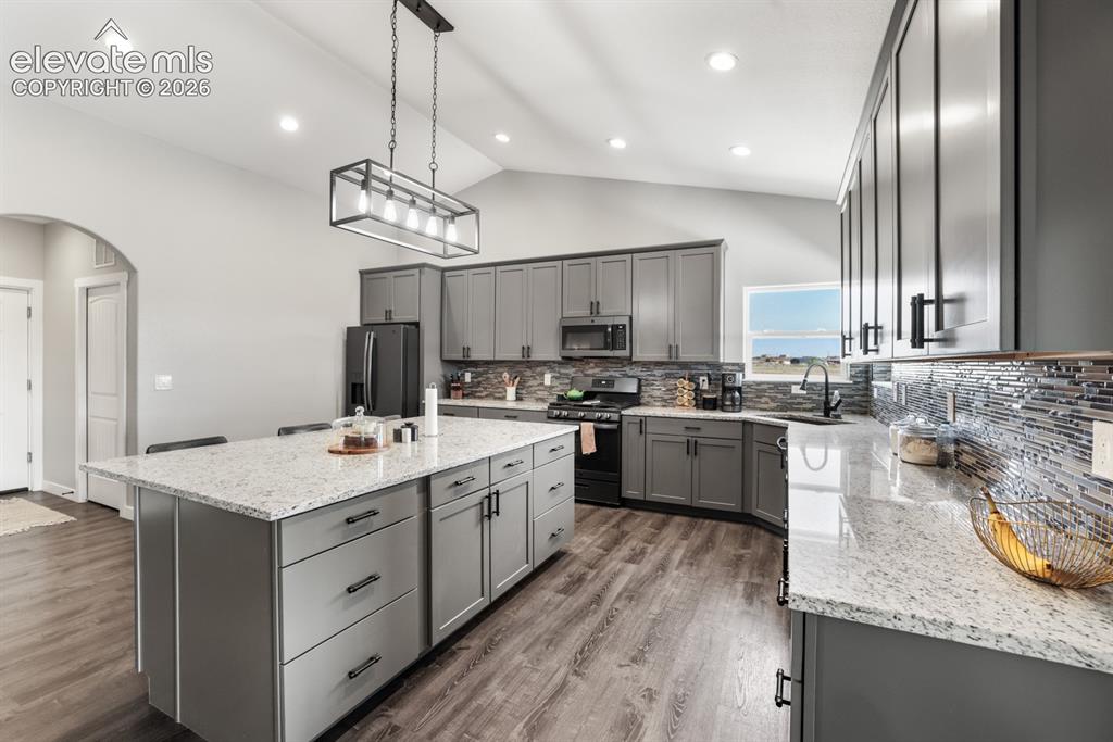 Image 9 of 50: Kitchen featuring a large central island with light-toned countertops, gray