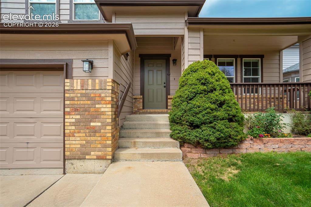 Image 3 of 50: Warm exterior siding with brick accents, covered front porch with railings,