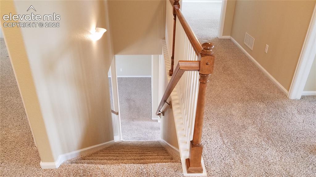Image 11 of 32: Carpeted staircase featuring a wood newel post and handrail, white baluster