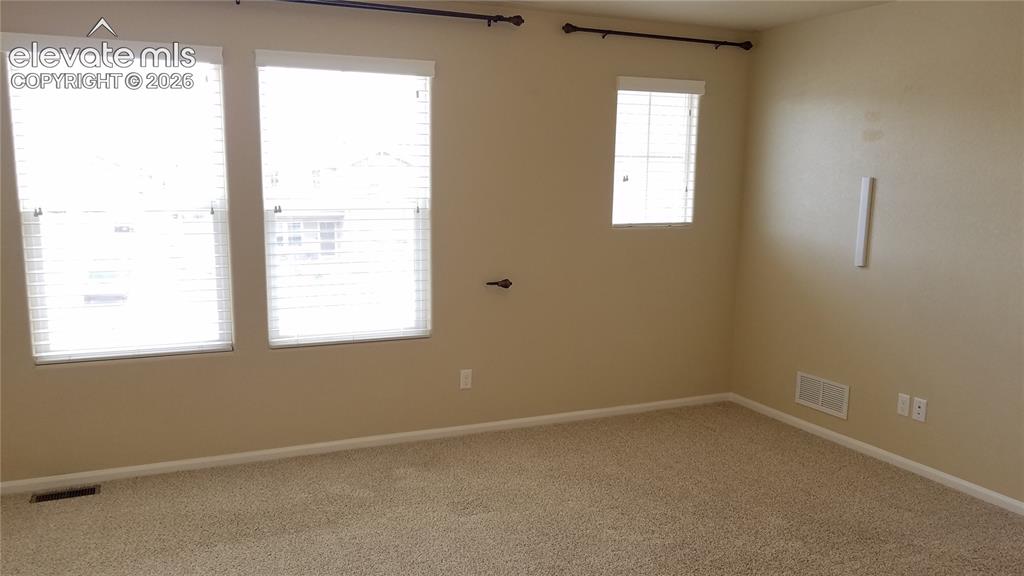 Image 13 of 32: Carpeted room with multiple windows, featuring light beige wall paint and w