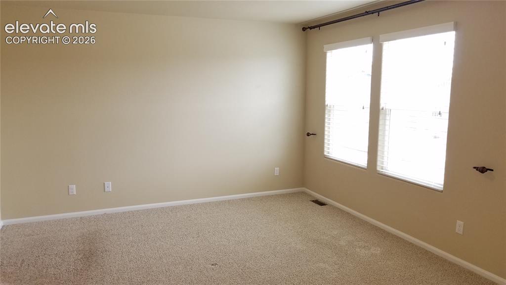 Image 14 of 32: Carpeted room featuring two windows with horizontal blinds and a curtain ro