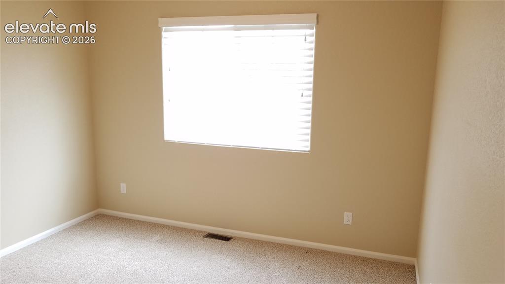 Image 15 of 32: Carpeted interior space featuring a window with horizontal blinds, neutral 