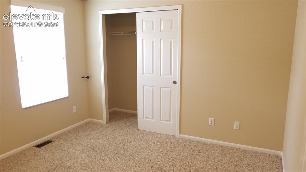 Image 19 of 32: Carpeted room featuring a white paneled closet door, a single window with b