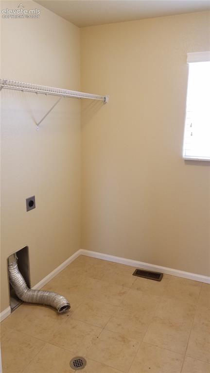 Image 23 of 32: Utility space featuring a wire shelf, tiled flooring, and a window with bli