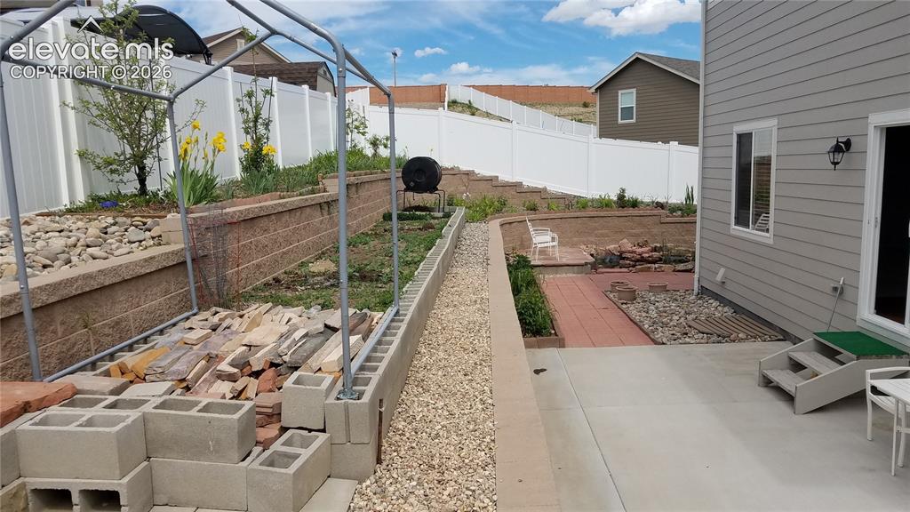 Image 29 of 32: Expansive backyard featuring a concrete patio, terraced landscaping with re