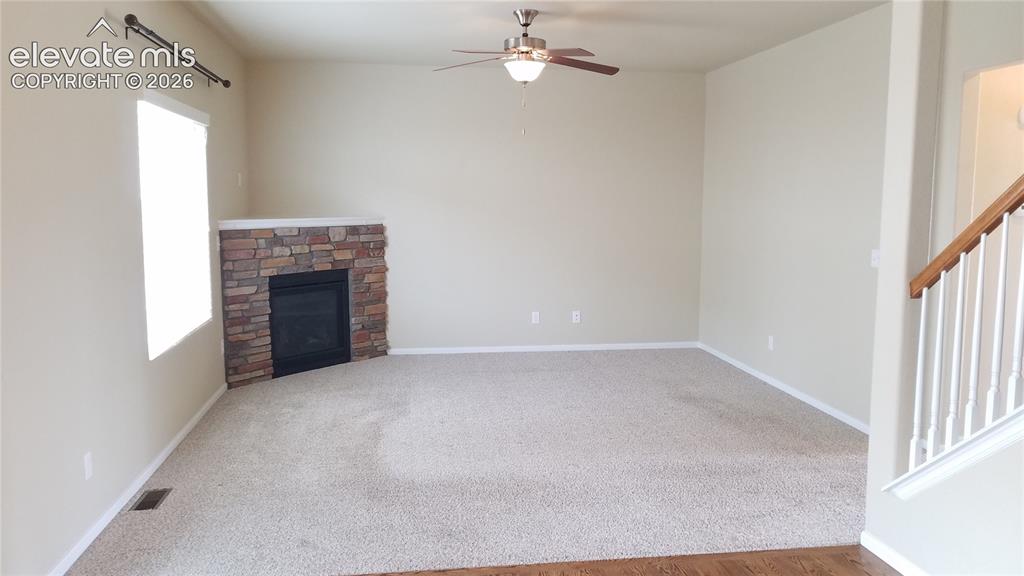 Image 4 of 32: Spacious living area featuring a corner fireplace with stone surround, neut