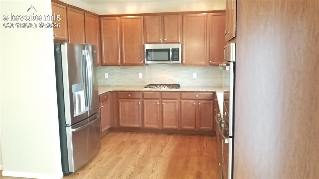 Image 5 of 32: Well-appointed kitchen featuring wood-finish flooring, ample cabinetry, sta
